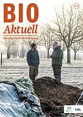 Titelseite Bioaktuell 3|24: Zwei Männer im Gespräch stehen auf einem Feld, im Hintergrund sind Bäume, im Vordergrund ein Komposthaufen.