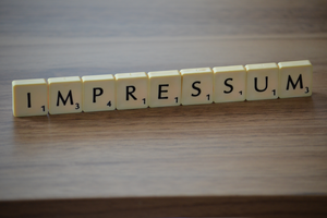 Das Wort Impressum mit Buchstaben auf einem Tisch.