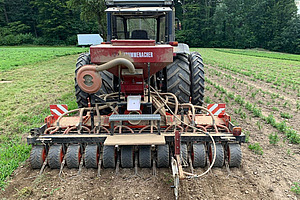 roter Traktor mit Saemaschine auf einem Feld