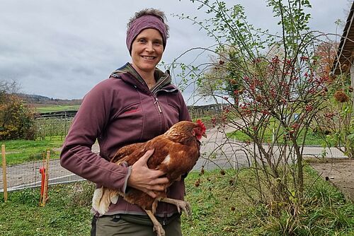 Eine Frau mit einem Huhn im Arm.