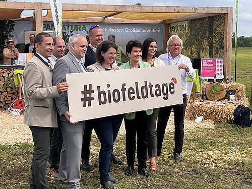Mehrere Personen halten ein Banner mit der Aufschrift #biofeldtage.