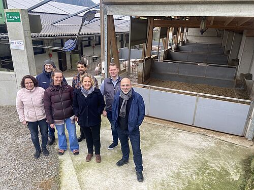 Eine Gruppe von sieben Personen vor den Auläufen des Schweinestalls.