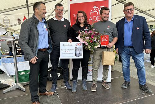 Vier Männer und eine Frau posieren in einem Festzelt.